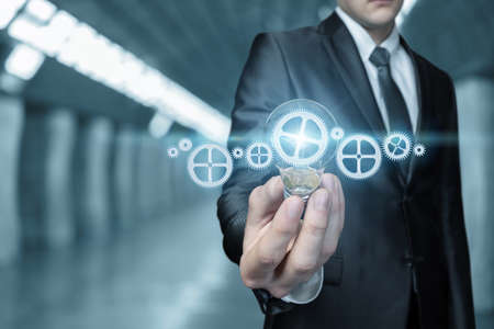 Business man shows a burning light bulb on the background of a business management mechanism.