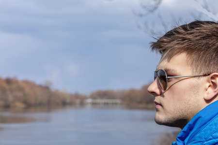 Young guy in sunglasses on the background of the river.の写真素材