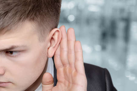 Young business man listens on blurred background.の写真素材