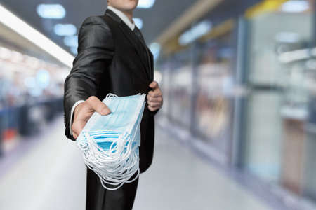 Businessman holds out a pack of protective masks on a blurred background.の写真素材