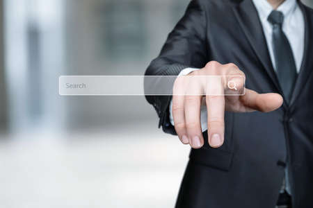 Young businessman clicks search bar on blurred background.の写真素材