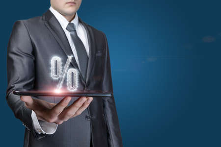 Businessman showing percentage on a tablet on a blue background.の写真素材