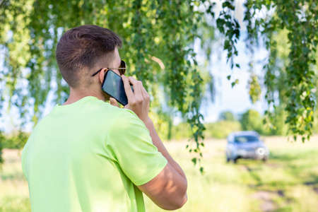 Young man talking on the phone near the car.の写真素材