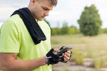 Male athlete looking at the phone on a blurred background.の写真素材