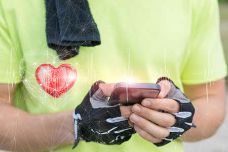 Young fitness athlete checks his heartbeat on a mobile device.の写真素材
