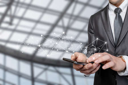 Business man working on the net on a mobile device on a blurred background.