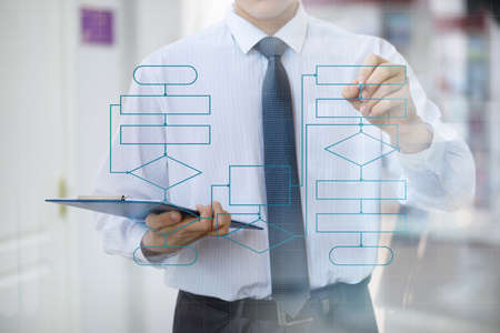 Businessman on glass draws a flowchart diagram of the program on a blurred background.の写真素材