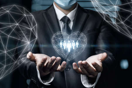 Businessman supports the heart in which customers are on a blurred background.の写真素材