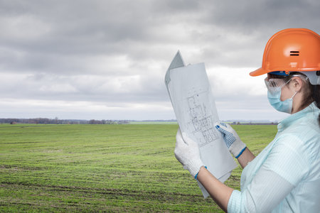 The concept of designing a house on the site. Engineer looks at the project on the background of the site.の写真素材