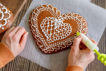 Woman decorate Christmas gingerbread in the shape of a heart.の写真素材