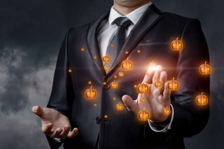 Business man clicks on a pumpkin in halloween on a dark background.の写真素材