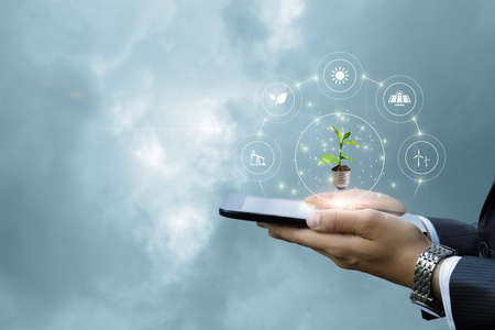 Business man shows alternative types of energy on the background of the sky on the tablet.の写真素材