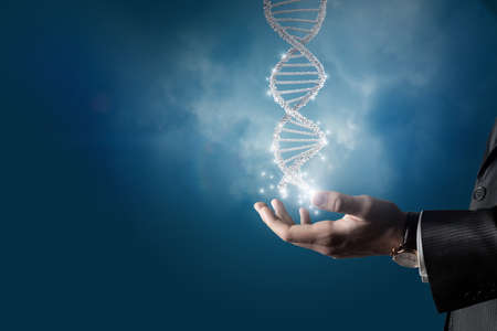 Business man shows human DNA molecule on blue background.の写真素材