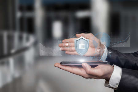Business man on mobile device with protective gesture hand protects investment.の写真素材
