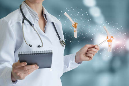 Doctor shows a model of a joint on a virtual screen on a blurred background.