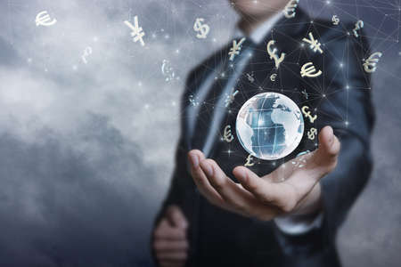 Businessman supports the international currency market in his hand against the background of the sky.の写真素材