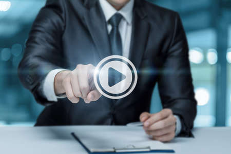 A man in a business suit and clicks on the Play icon on a blurred background.