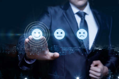 Business man clicks on a smiley with a smile on a blurred background.の写真素材