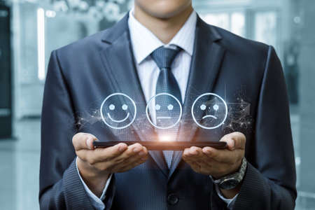 Business man shows emoticons on a tablet as a rating on a blurred background.の写真素材