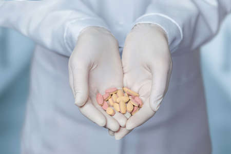 Pill treatment concept. Doctor in rubber gloves shows pills.の写真素材