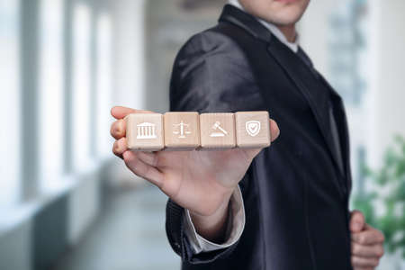 The concept of protecting business in courts. Businessman show cubes with icons of justice.