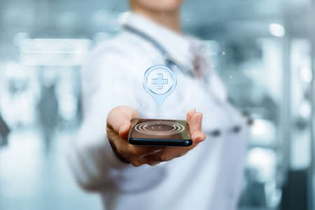 The doctor shows the location of the medical institution on the phone.の写真素材