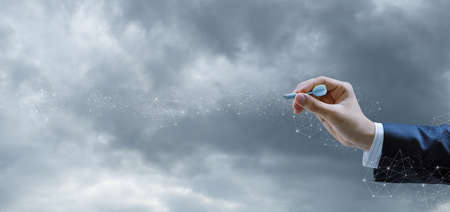 The concept of aiming in business. Hand with a dart of a businessman on the background of the...