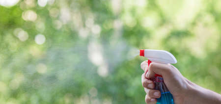 A hand with a spray splashes a cleaner on a blurred background.の写真素材