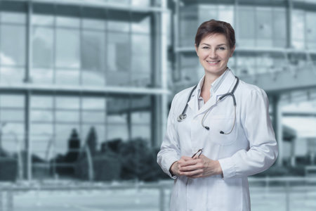 Female doctor stands on a blurred background in front of the hospital.の写真素材