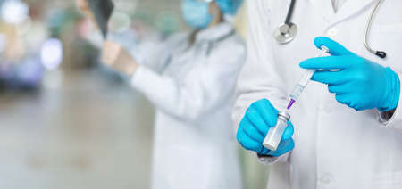 Doctor prepares a vaccine on a blurred background hospital.