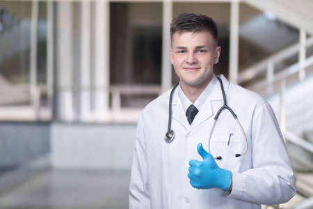 Young doctor showing good with hand on blurred background.の写真素材