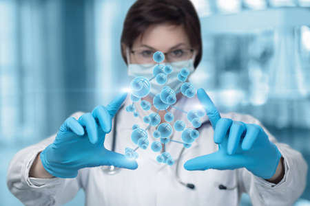 Molecular research concept. A laboratory assistant manipulates a molecule on a blurred background.の写真素材
