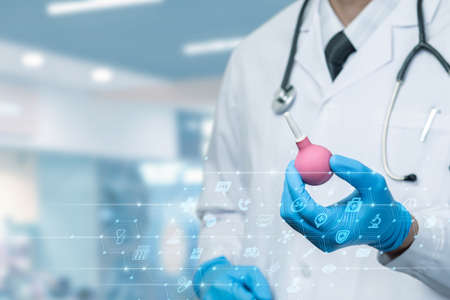 The doctor shows an enema for the procedure against the background of medical icons.の写真素材