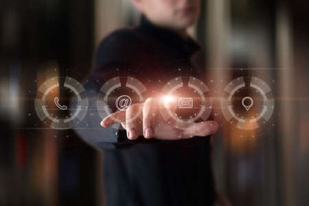 Man clicking on a virtual computer screen on a contact icon.の写真素材