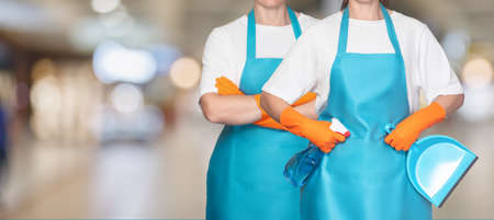 A group of cleaners stand in front of a blurred background of a shopping mall.