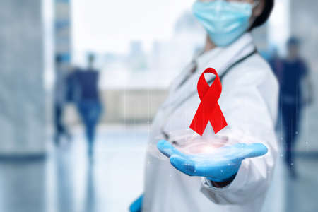 The doctor shows a red ribbon as a symbol of the fight against AIDS and cancer.の写真素材