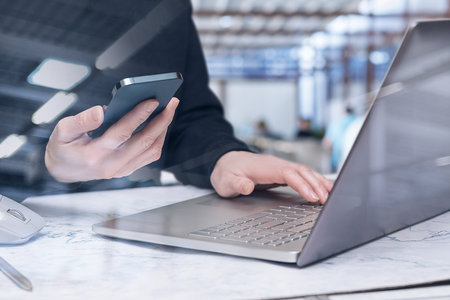 Businessman works on the phone and laptop at the same time against the backdrop of the office.の写真素材