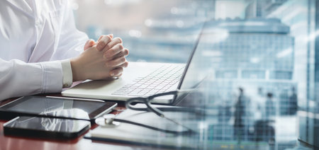 Concept of medical consultation and diagnosis. The doctor sits at a computer on a blurred background.の写真素材