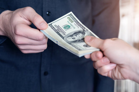 Passes a stack of dollars on a blurred background closeup.