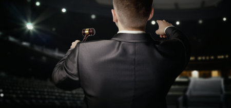 The auctioneer conducts an auction in the background of the hall.の写真素材