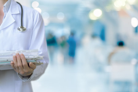 The doctor holds case histories in a stack of documents on the background of a polyclinic.の写真素材
