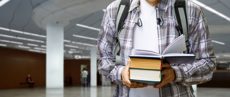 A student holds textbooks in his hands and prepares for classes on a blurred background.の写真素材