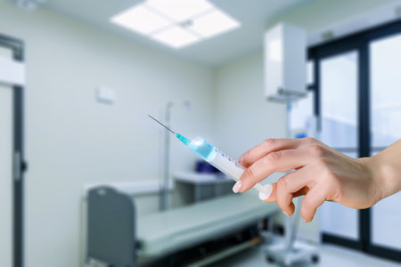 Hand with a syringe and medicine in the background of the room for injections.の写真素材