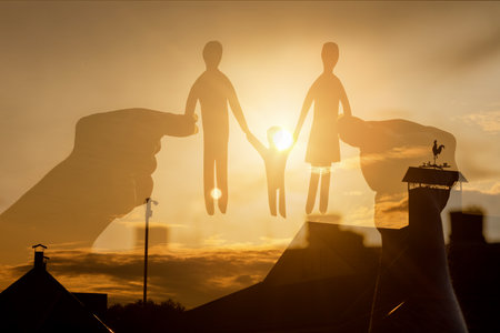 Young family support concept. Hands holding a paper-cut family against the backdrop of a sunset.