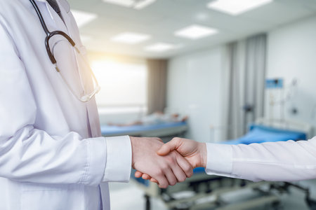 The doctor supports the patient with a handshake on a blurred background.の写真素材