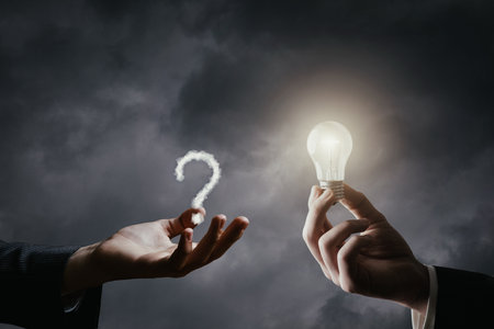 The concept of ideas for emerging issues. The hand gives an idea in the form of a burning light bulb to answer the question that has arisen.の写真素材