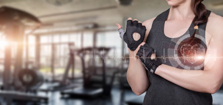 Concept of healthy cardio exercise in the gym. The woman measures the pulse against the backdrop of the gym.の写真素材