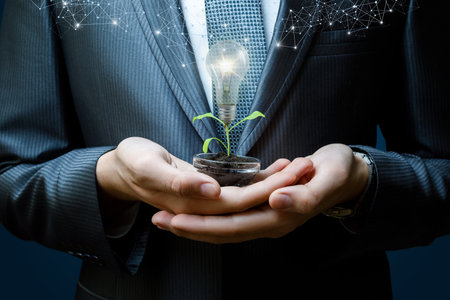 The concept of growing a creative idea in business. A businessman shows a plant with a light bulb instead of a flower.の写真素材