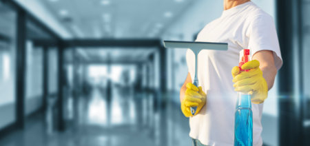 A cleaning lady stands with a spray on a blurred room being cleaned.の写真素材