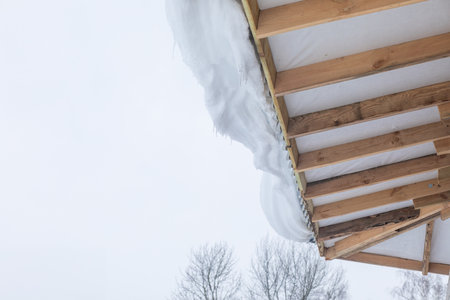A snowdrift on the roof overhang. The concept of snow load on the roof.の写真素材